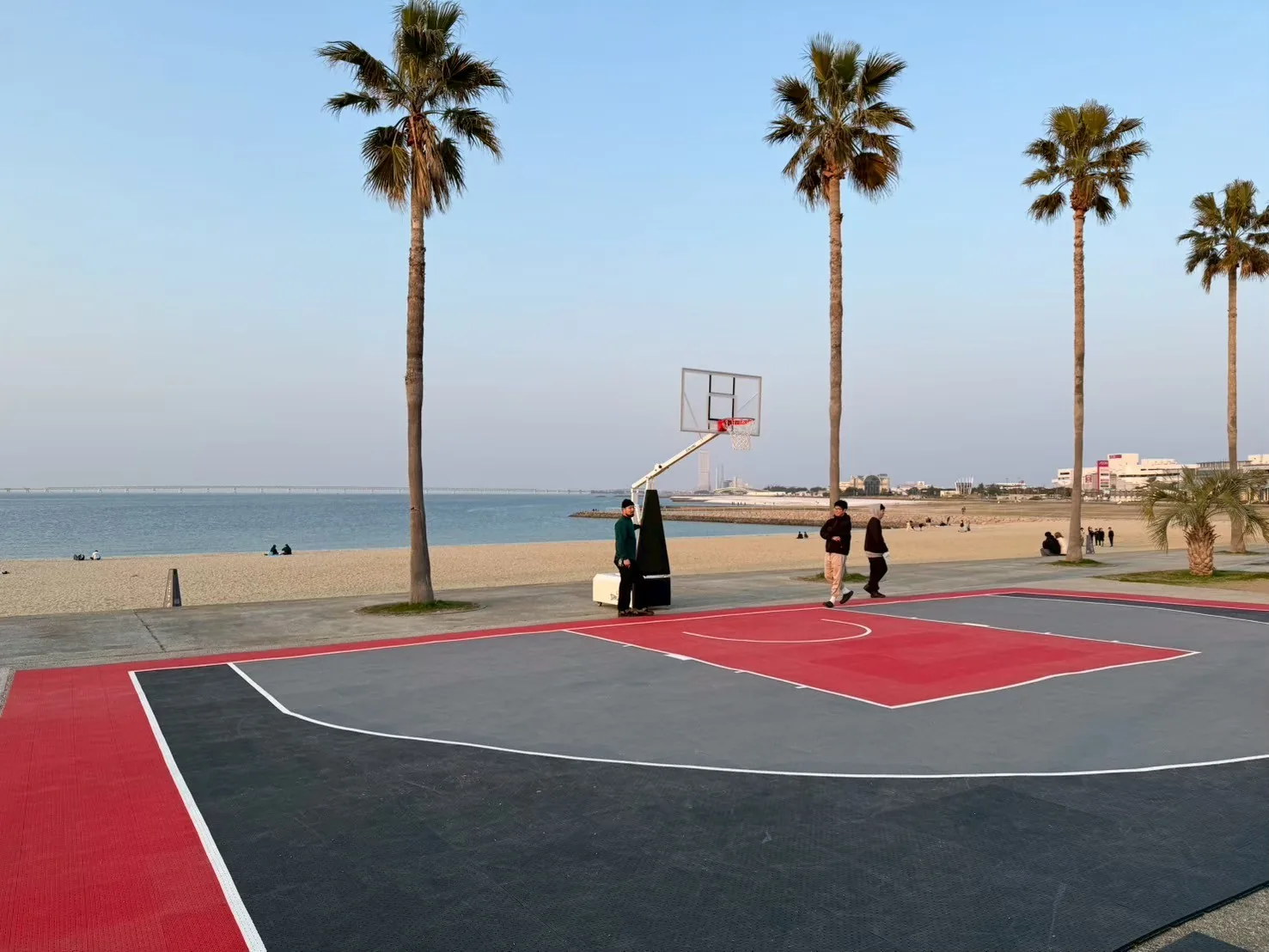 夕景の海辺に設営された ANOTHERCOURT の移動式 3×3 バスケットボールコート